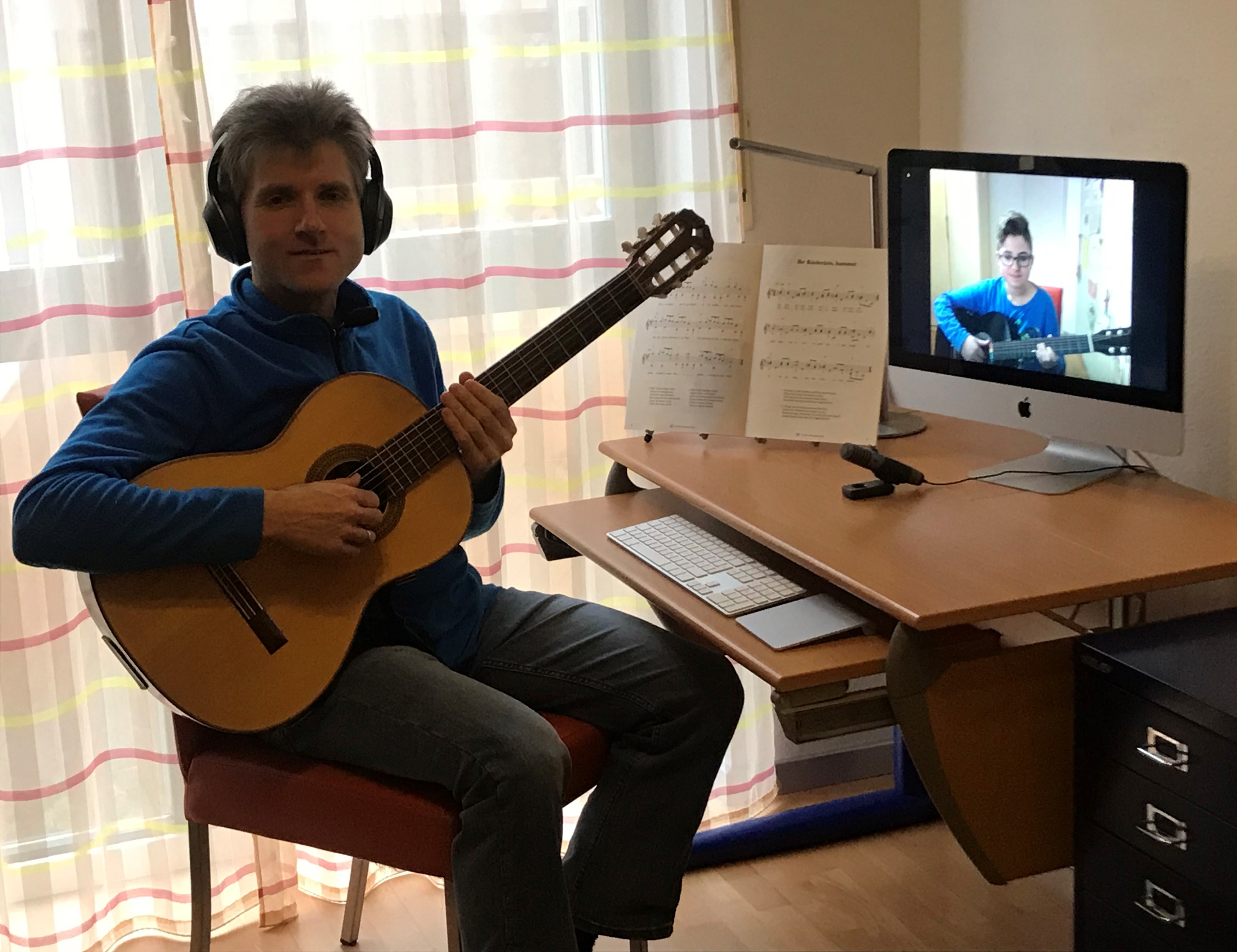 Thorsten Müller mit Gitarre und Kopfhörern vor seinem PC.