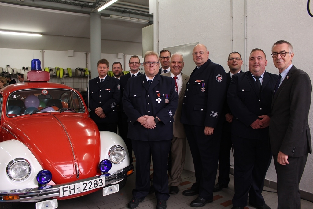 Gruppenbild der geehrten Feuerwehrmänner mit Auto in der Feuerwache.