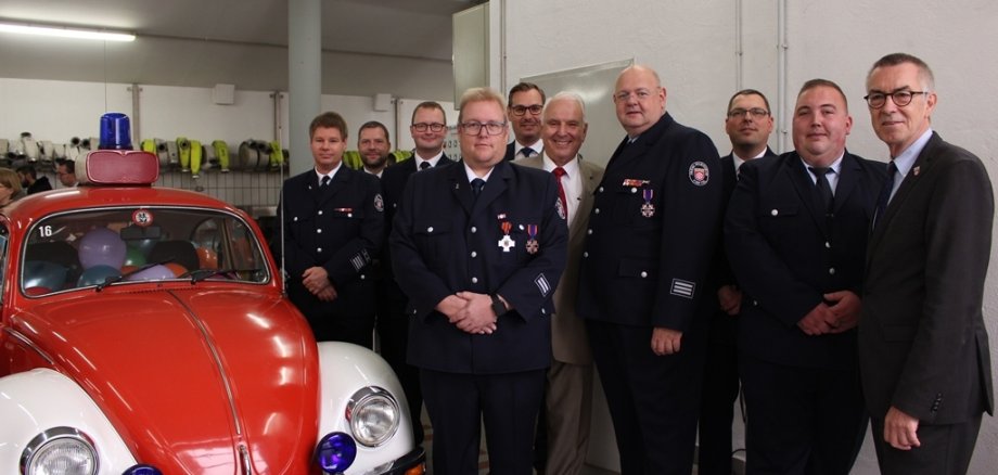 Gruppenbild der geehrten Feuerwehrmänner mit Auto in der Feuerwache.