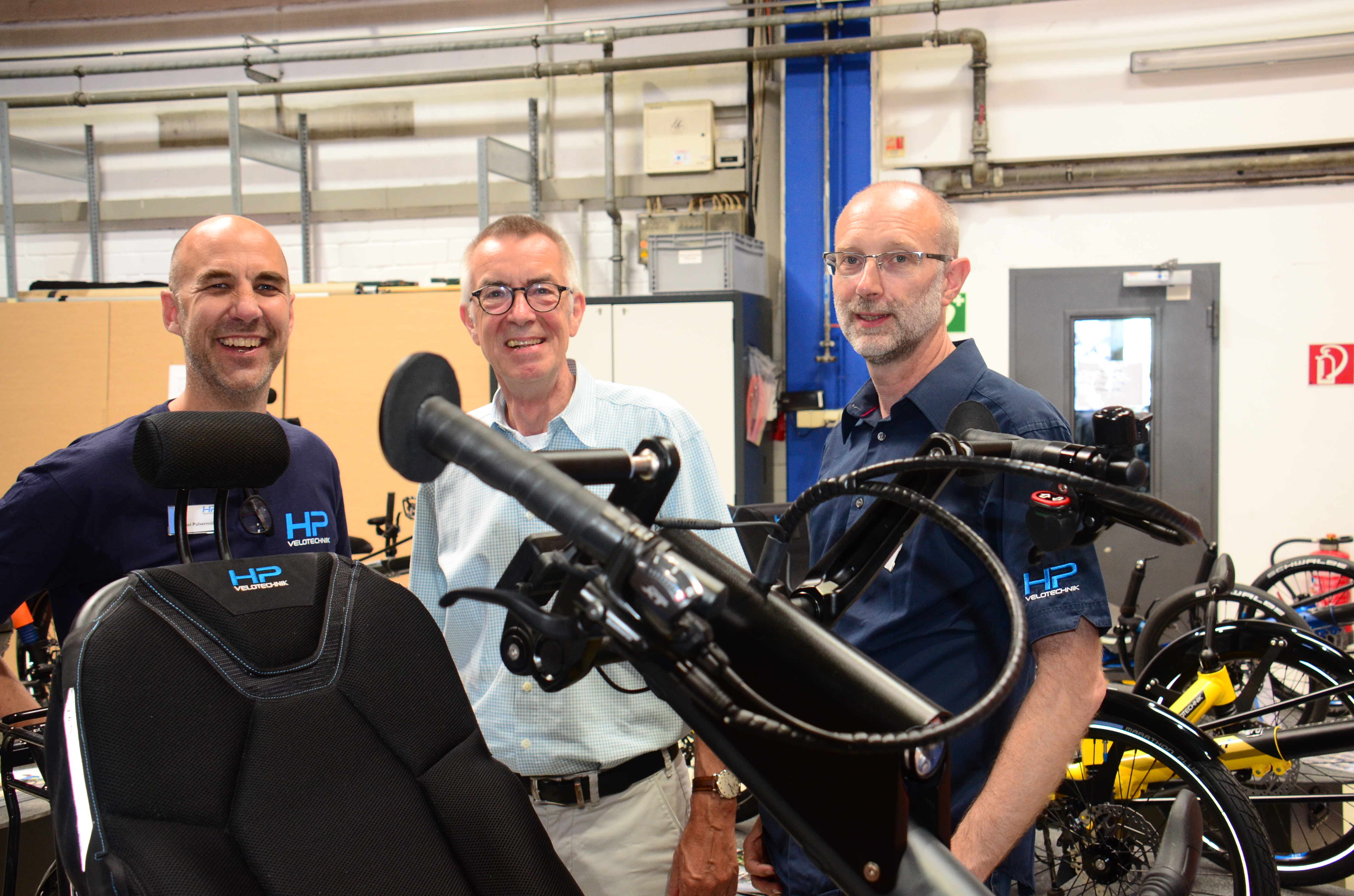 Franz Jirasek mit den Geschäftsführern an einem neuen Rad für behinderte Menschen.