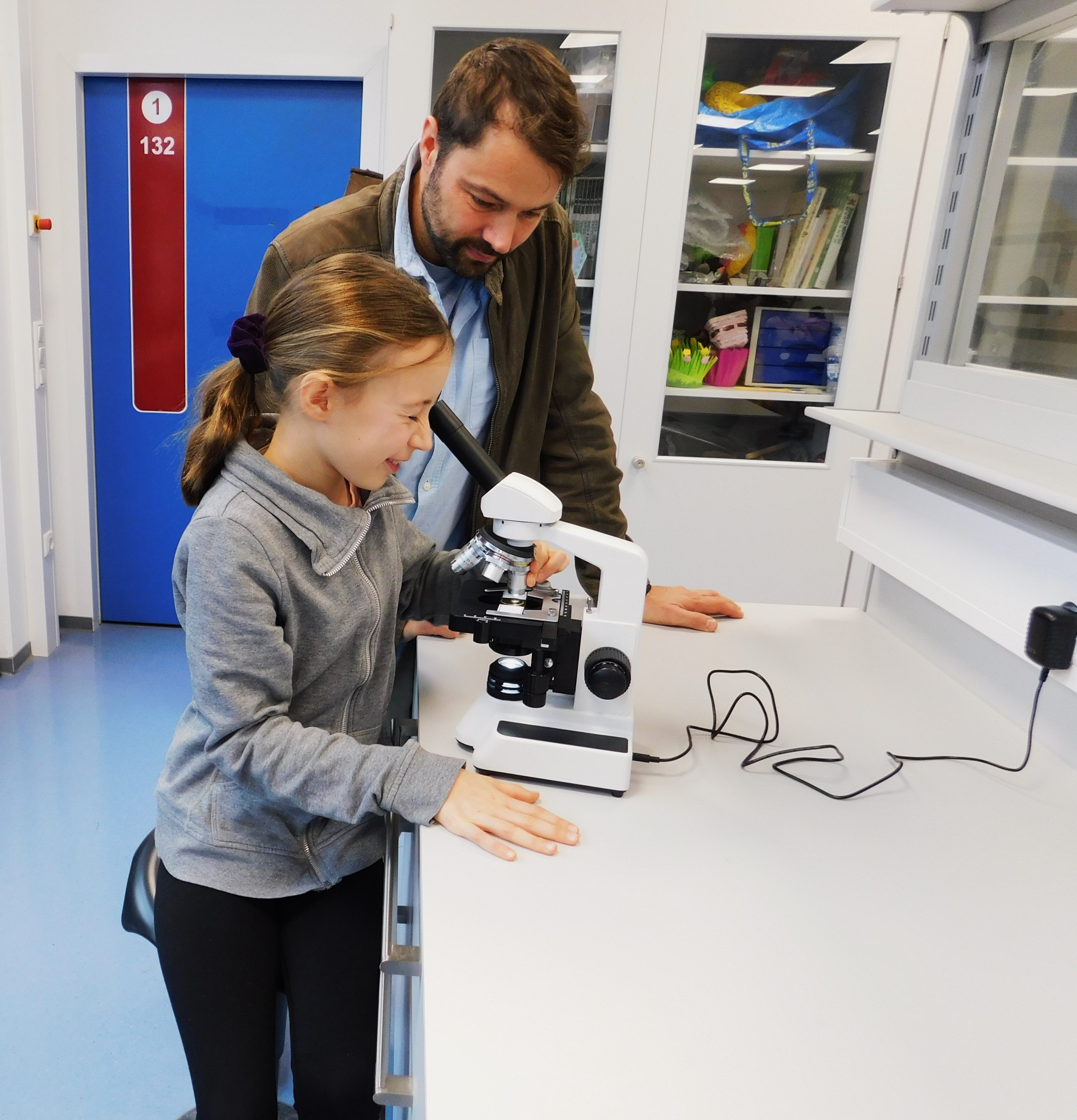 Mädchen schaut durch Mikroskop.