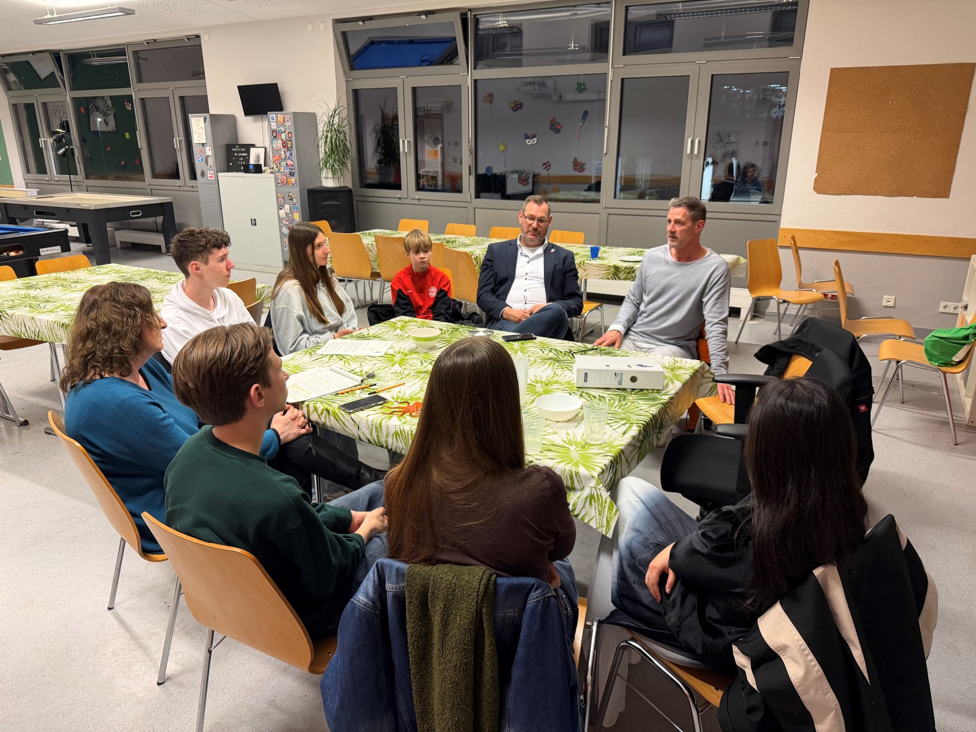 Jugendliche mit Erwachsenen an einem Tisch.