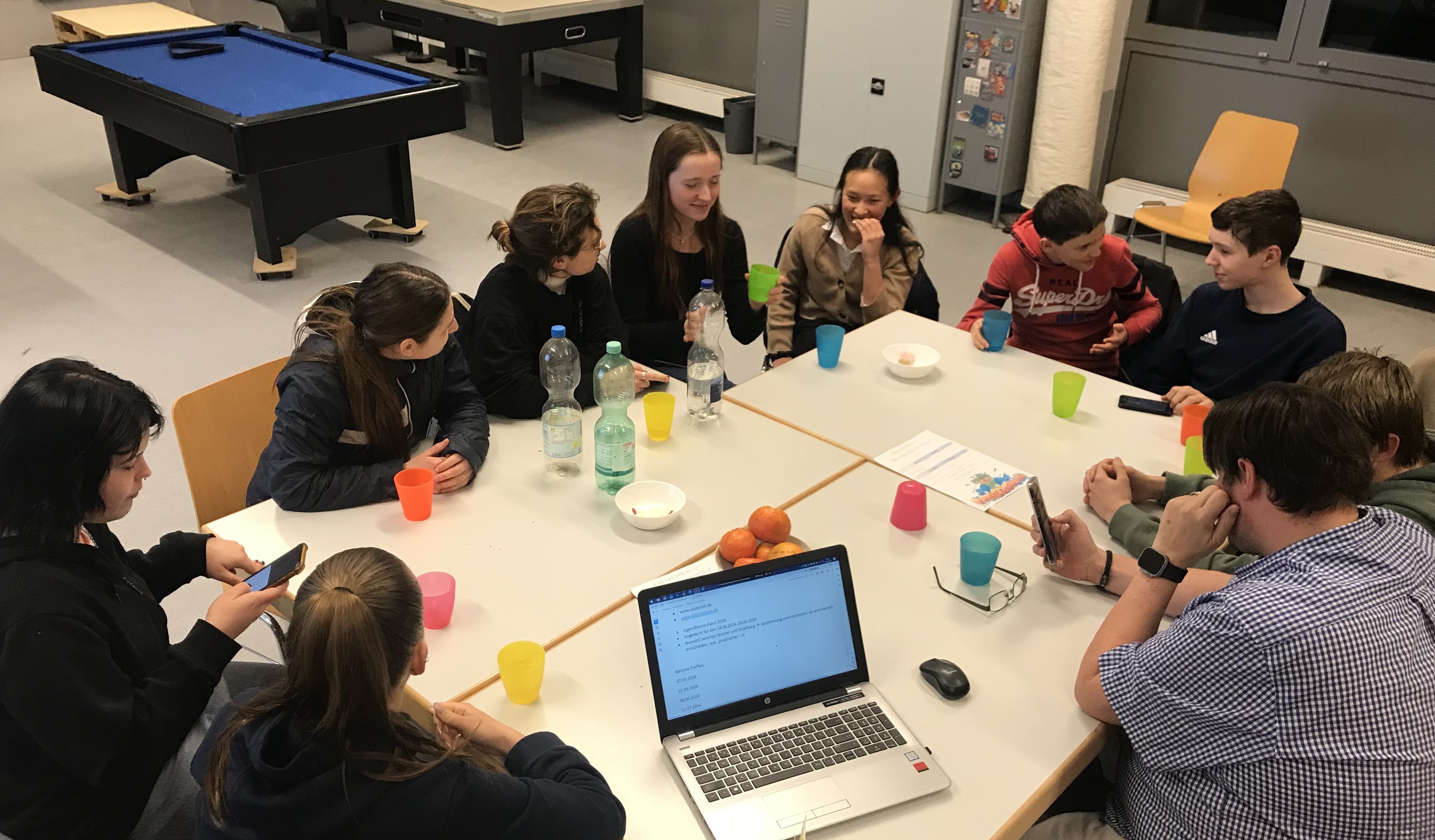 Jugendliche rund um Computertisch.