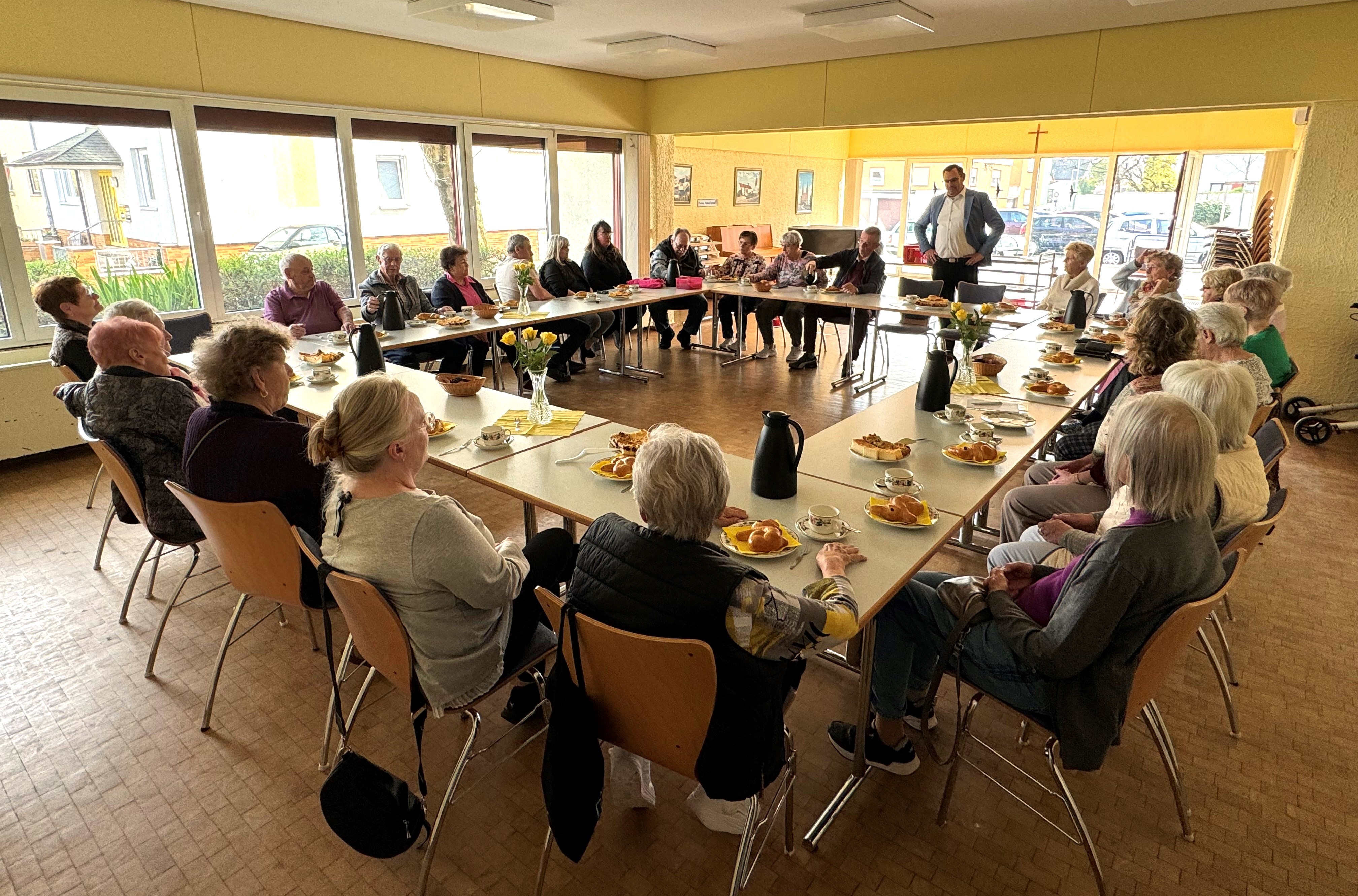 Die Bewohner an großer Kaffeetafel.