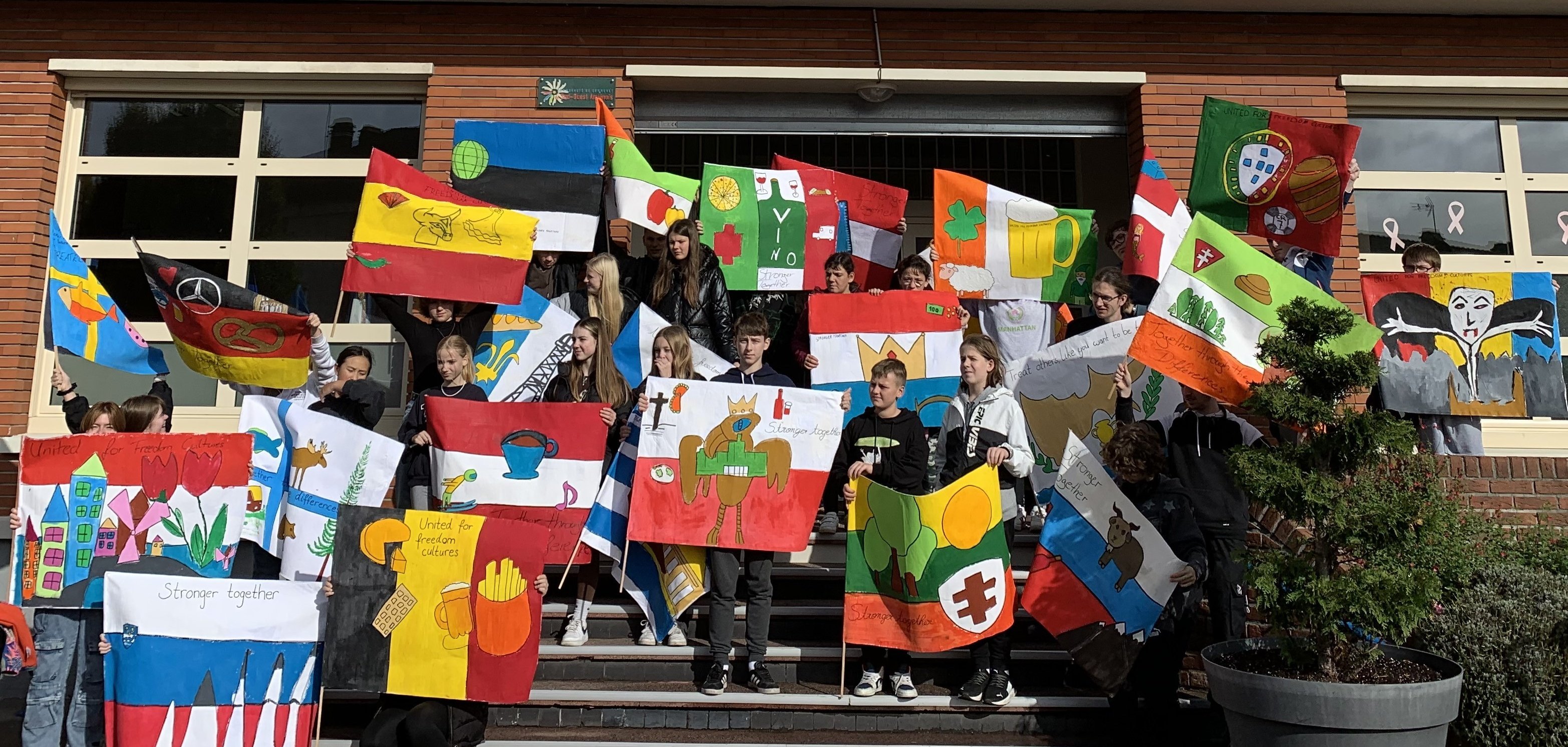 JUgendliche mit bunten Fahnen vor dem Rathaus in Airaines.