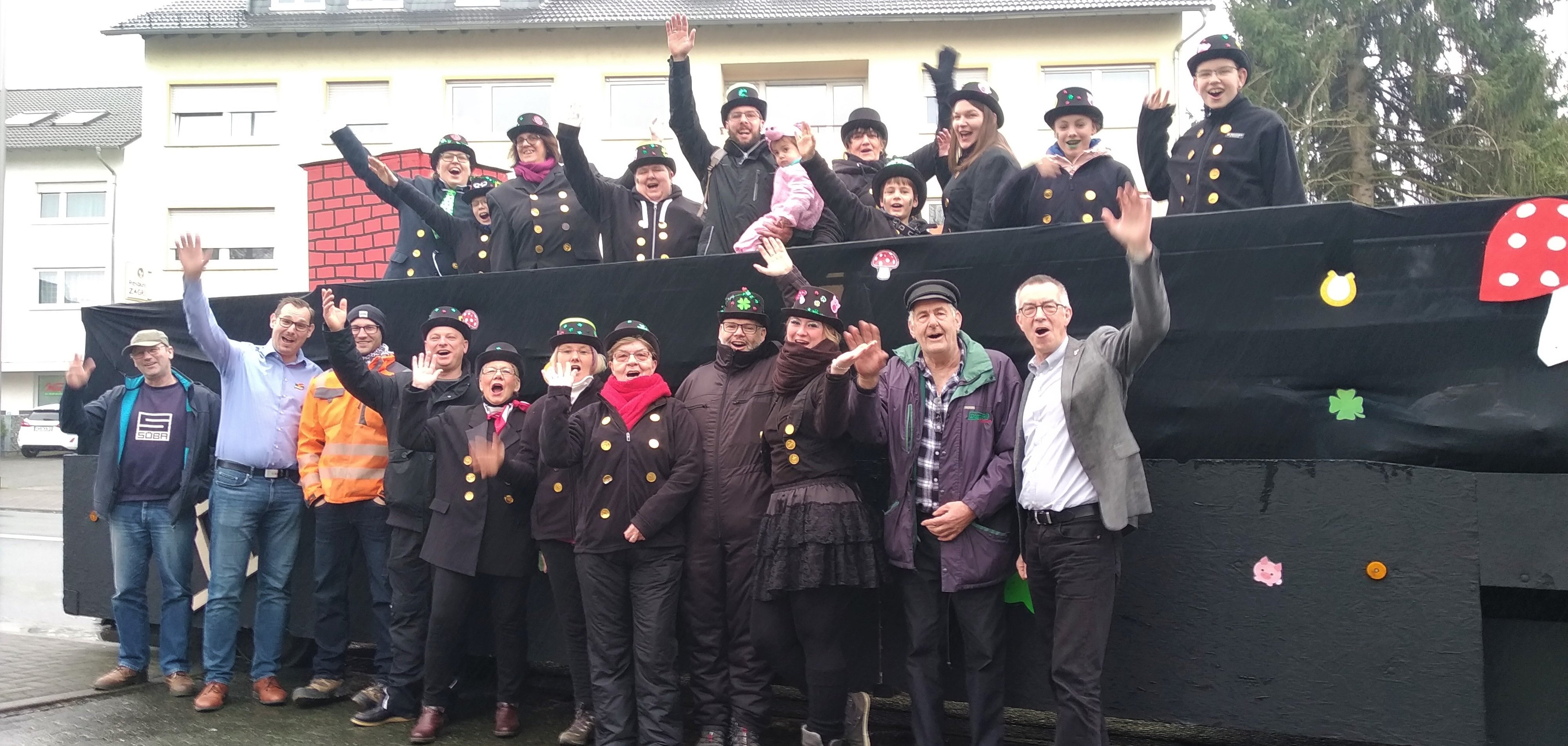 Die Mitglieder der Heimat- und Festwagengesellschaft stehen in Schornsteinfeger-Verkleidung vor ihrem Motivwagen.