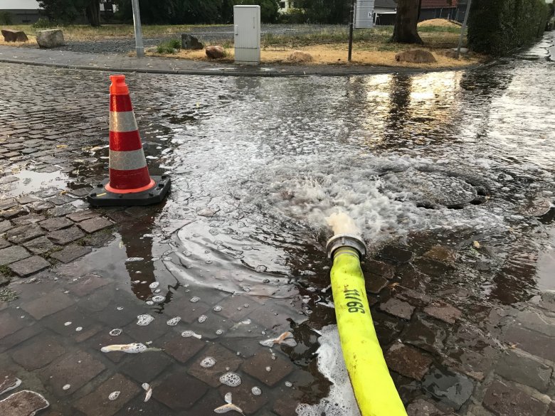 Aus einem Feuerwehrschlauch sprudelt Wasser.