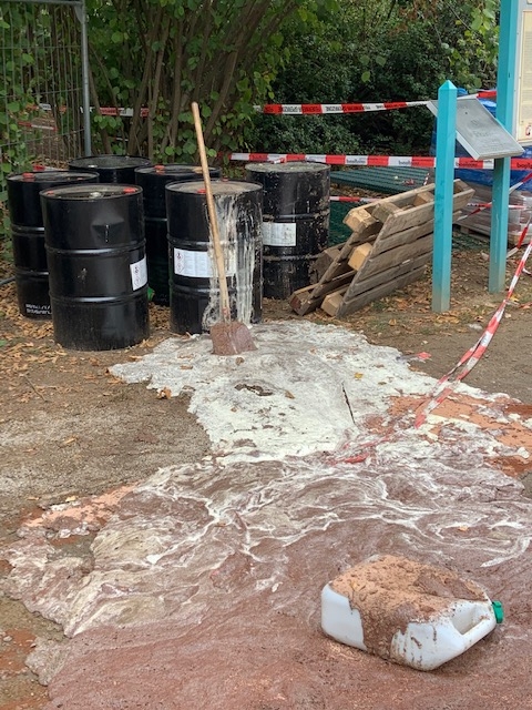 Ein schwarzes Fass mit Loch und jeder Menge aufgeschäumte Flüssigkeit drumherum.