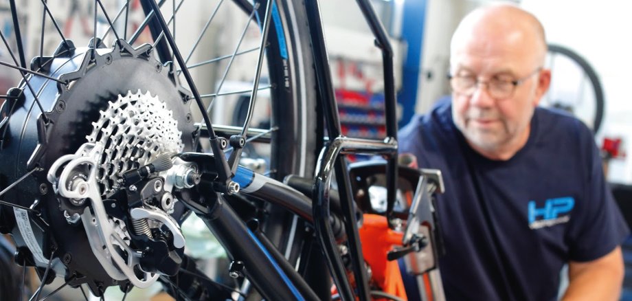 Ein Mitarbeiter der Firma Velotechnik schraubt an einer Fahrradfelge.