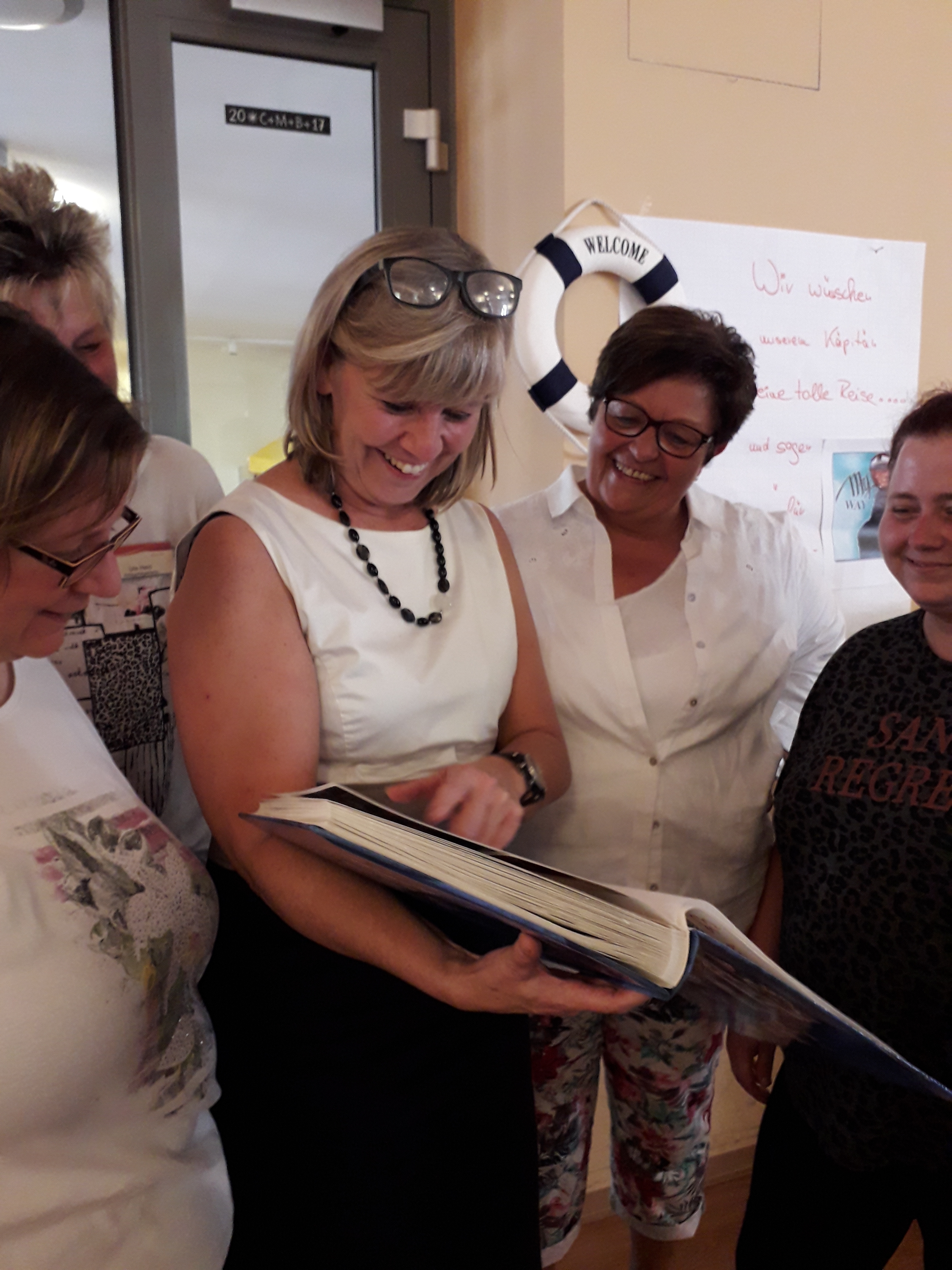 Jutta Vortkampp schaut sich - umringt von Kollegen - ein Fotoalbum an.