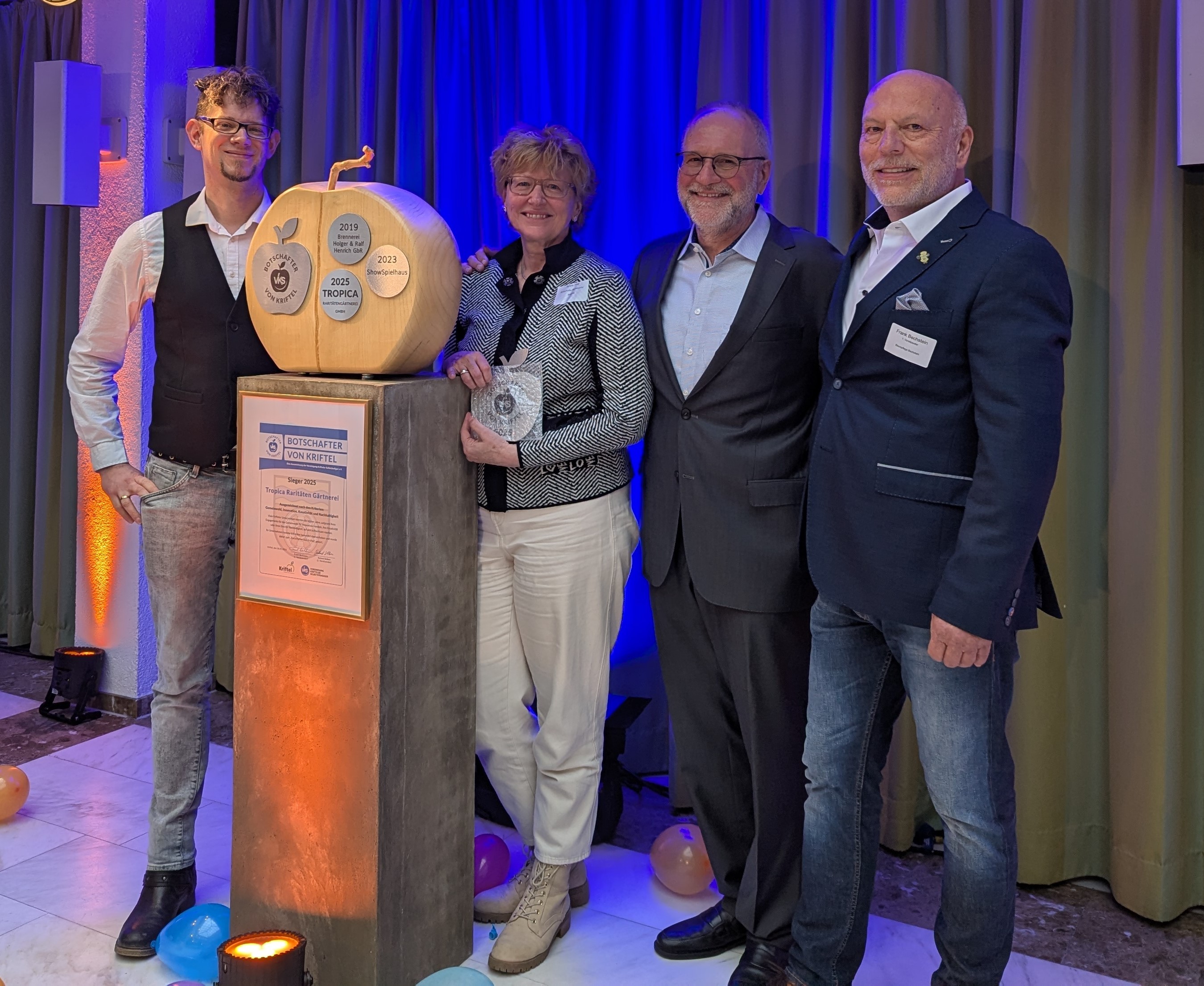 Familie May neben dem Holzapfel mit Ehrungsemblem.