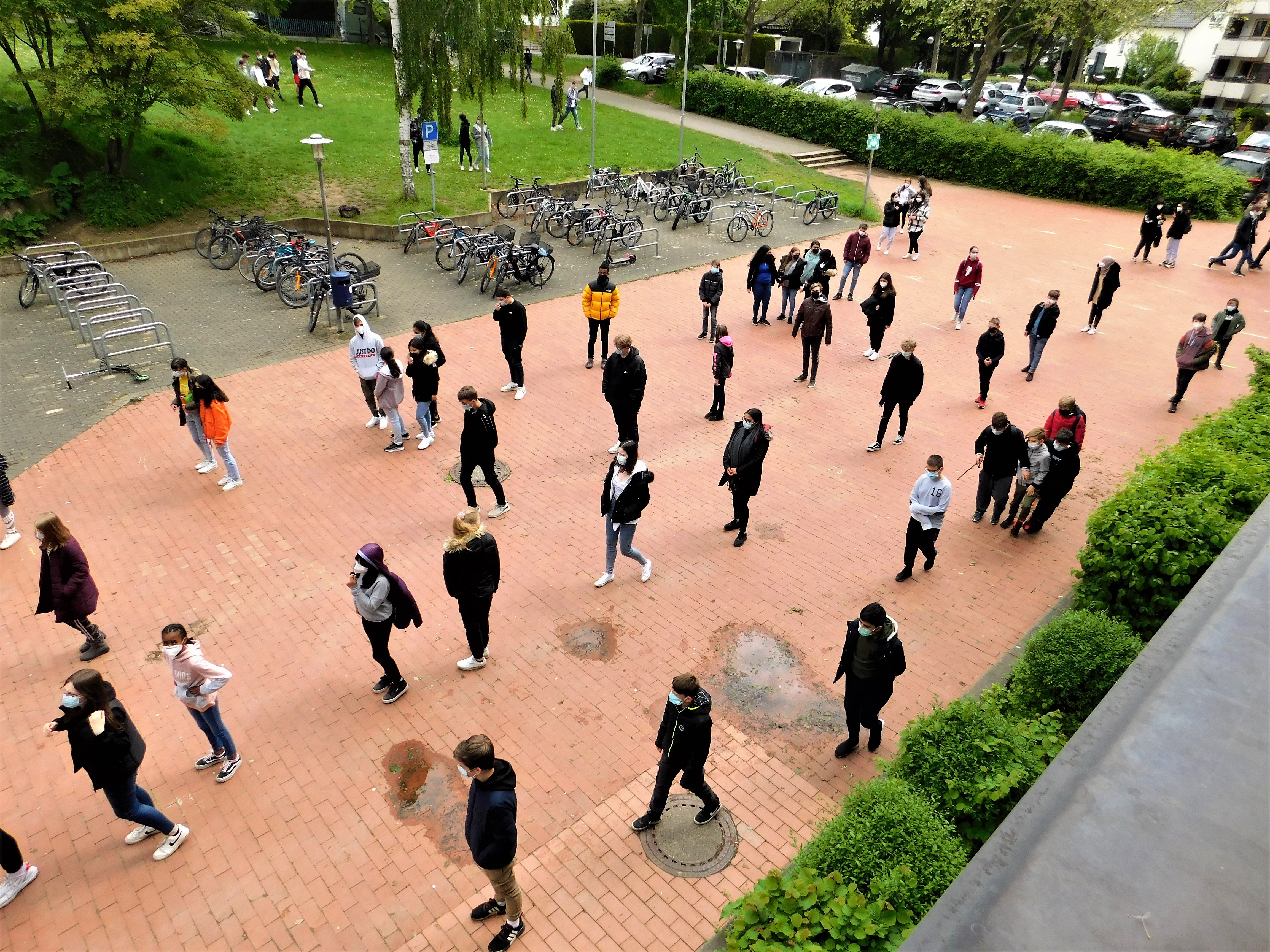 Schüler mit Masken stehen mit Abstand in Schlangen vor der Schule.