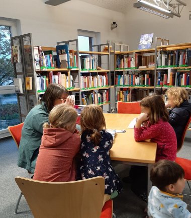 Eine Frau liest Kindern in der Bücherei vor.