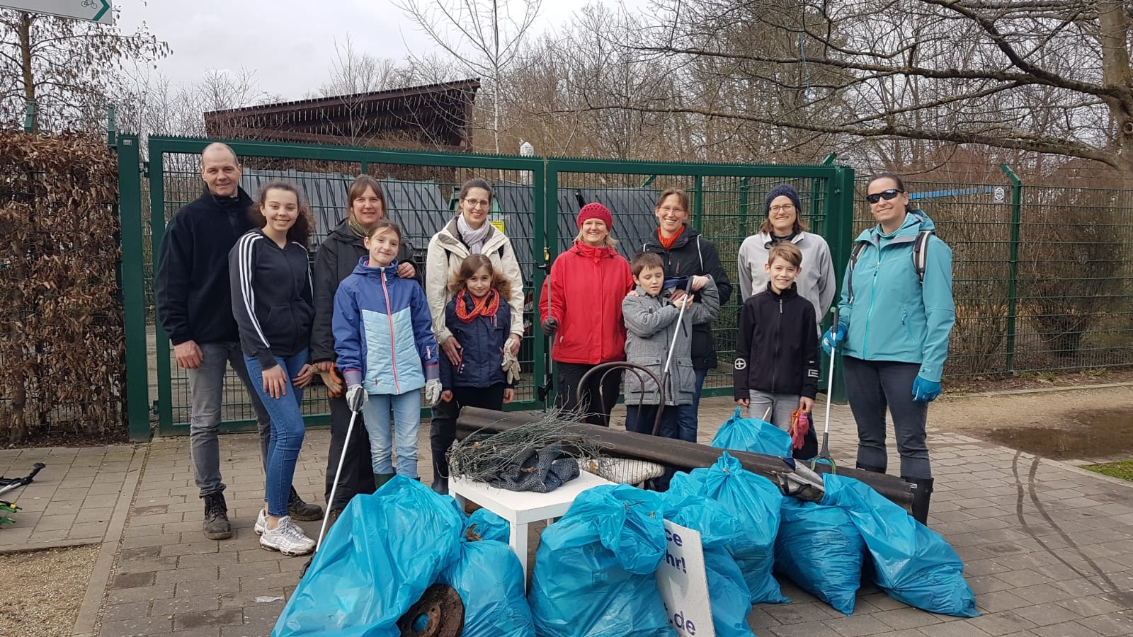 Eine Gruppe von Menschen, darunter Kinder, und jede Menge volle, blaue Müllsäcke.
