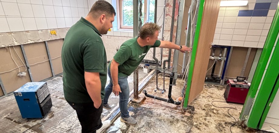 Der Erste Beigeordnete mit Handwerker in entkernter Küche.