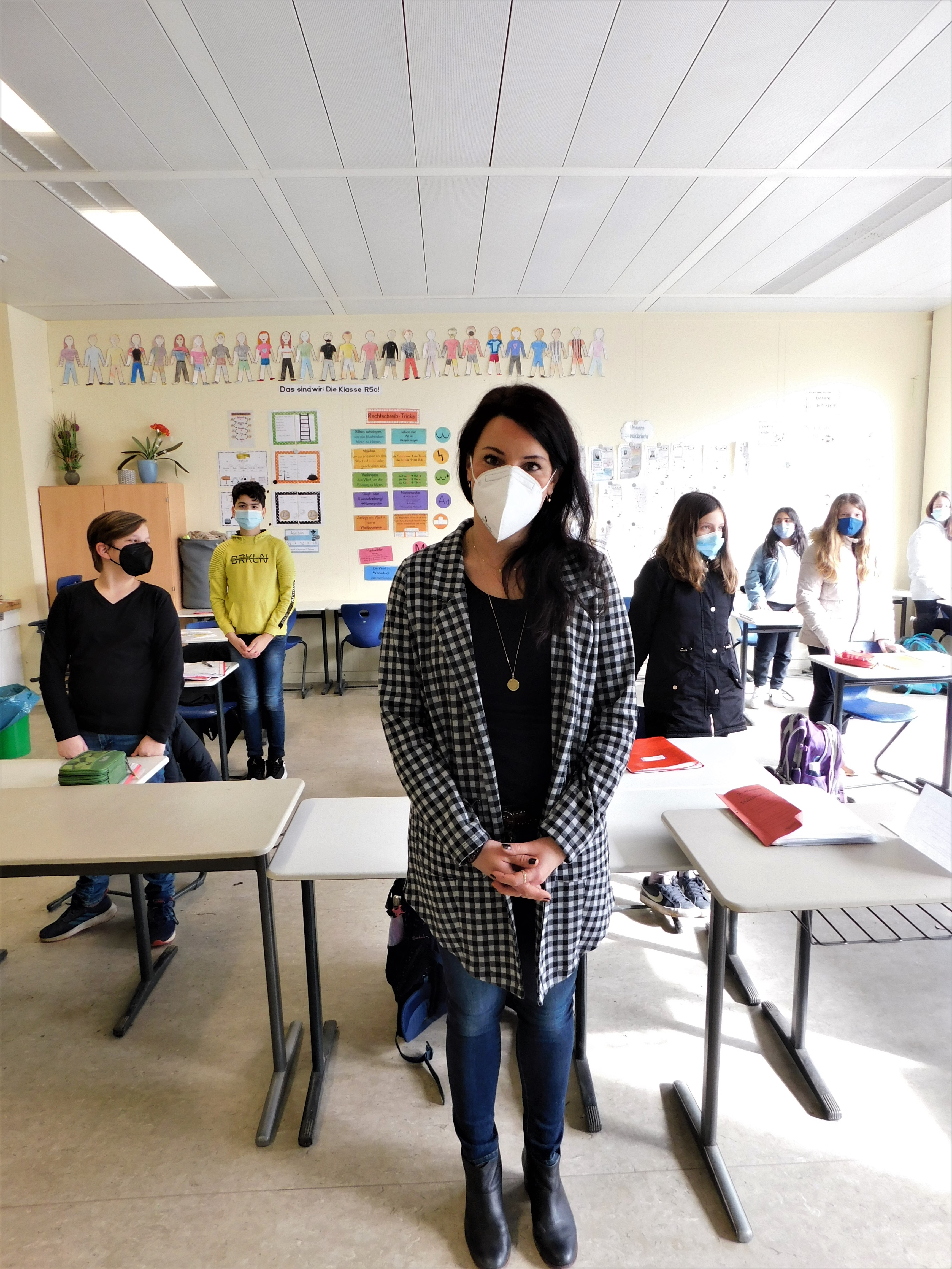 Lehrerin und Schüler mit Masken und Abstand.