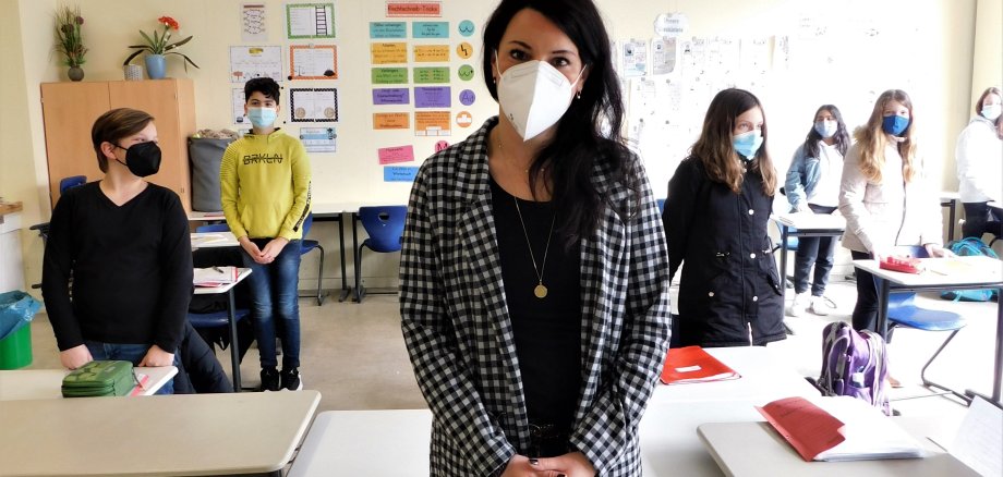 Lehrerin und Schüler mit Masken und Abstand.