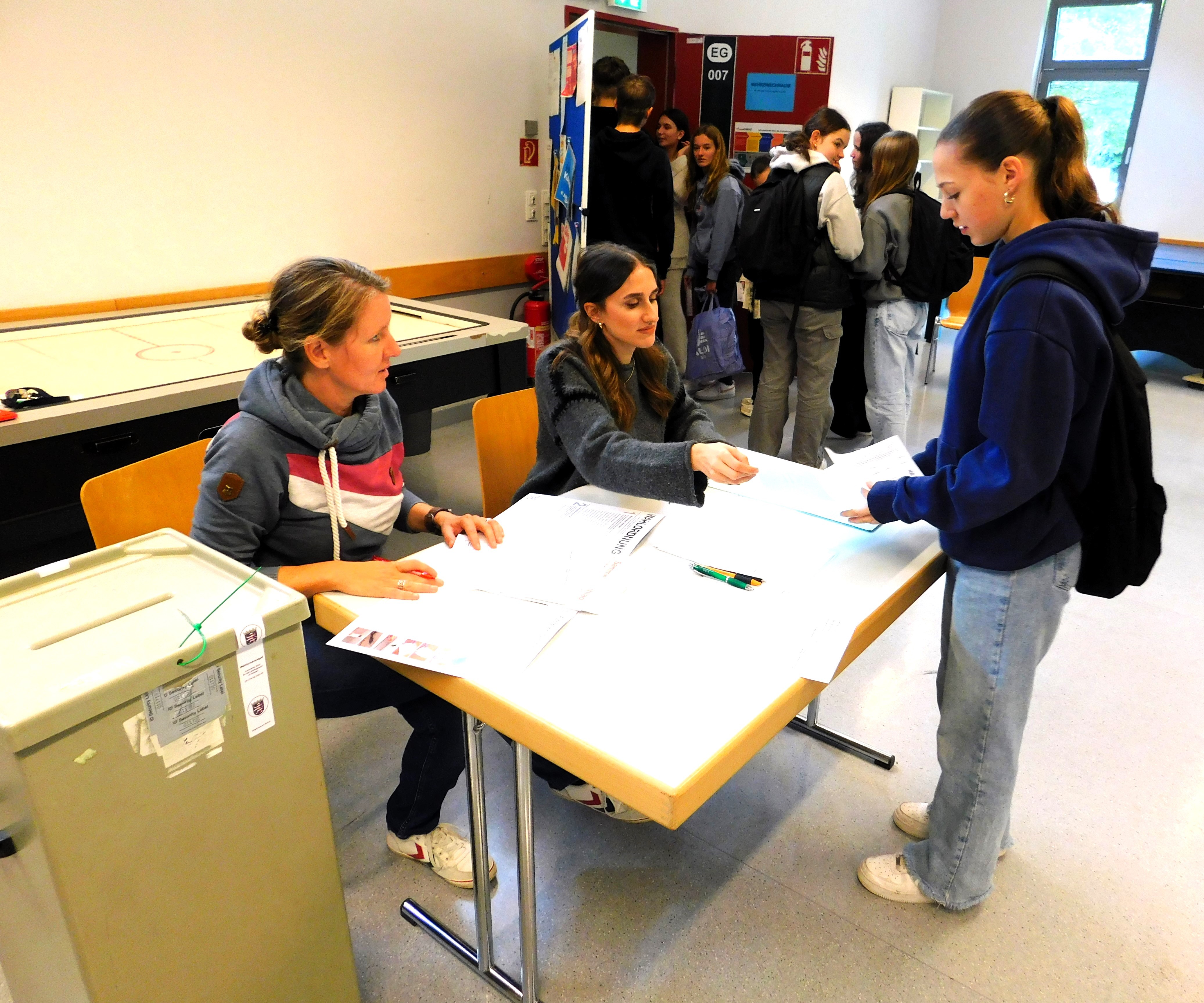 Mädchen hält Wahlzettel über einen Tisch.