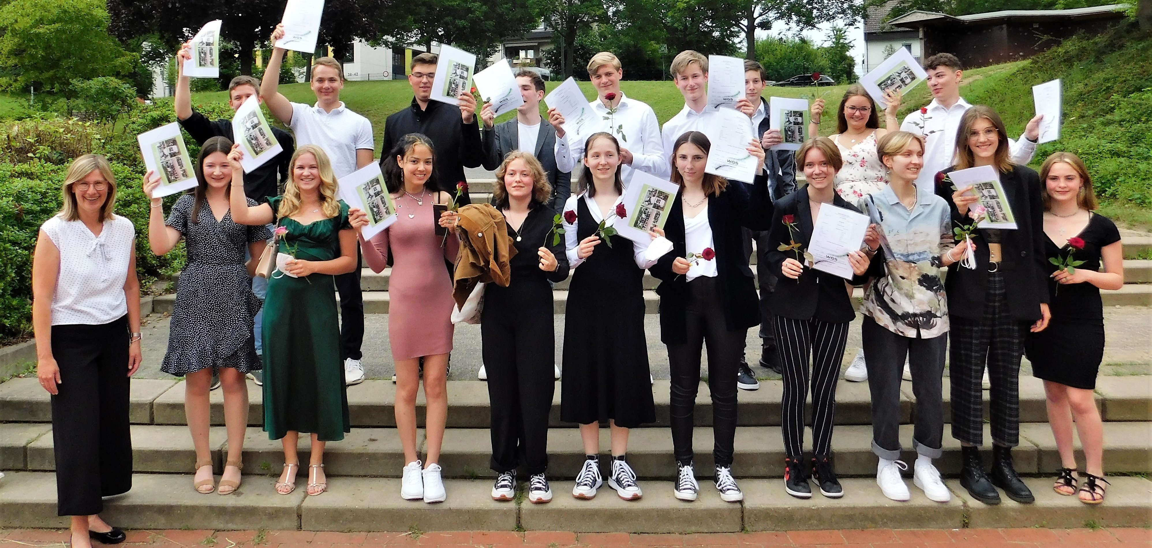 Eine Klasse auf dem Schulhof hält fröhlich Blumen in die Luft.