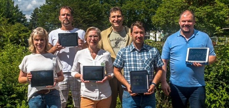 Das Schulleitungsteam auf dem Schulhof mit Laptops in der hand.
