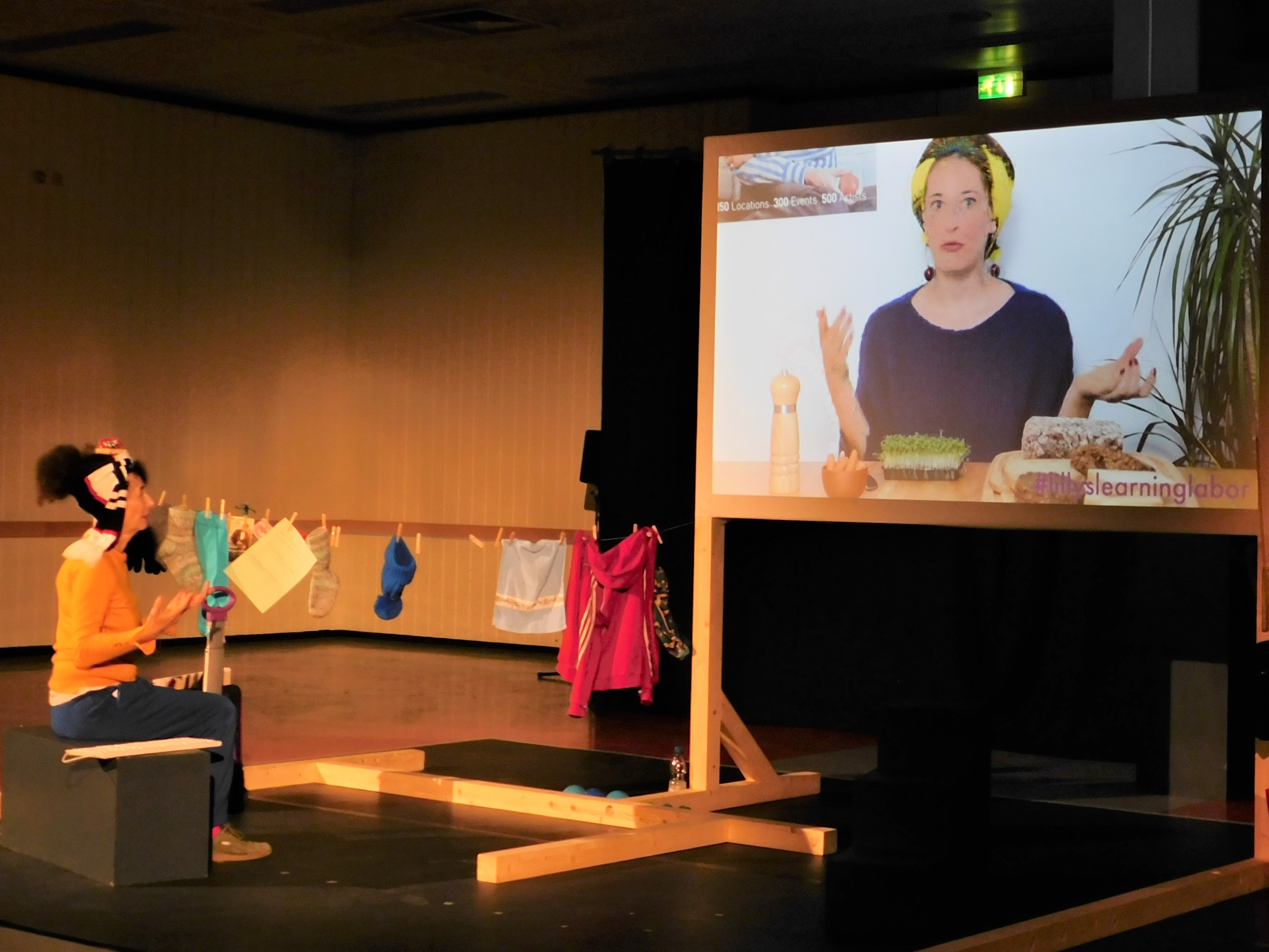 Die Schauspielerin neben einer Wäscheleine und einem großen Bildschirm.