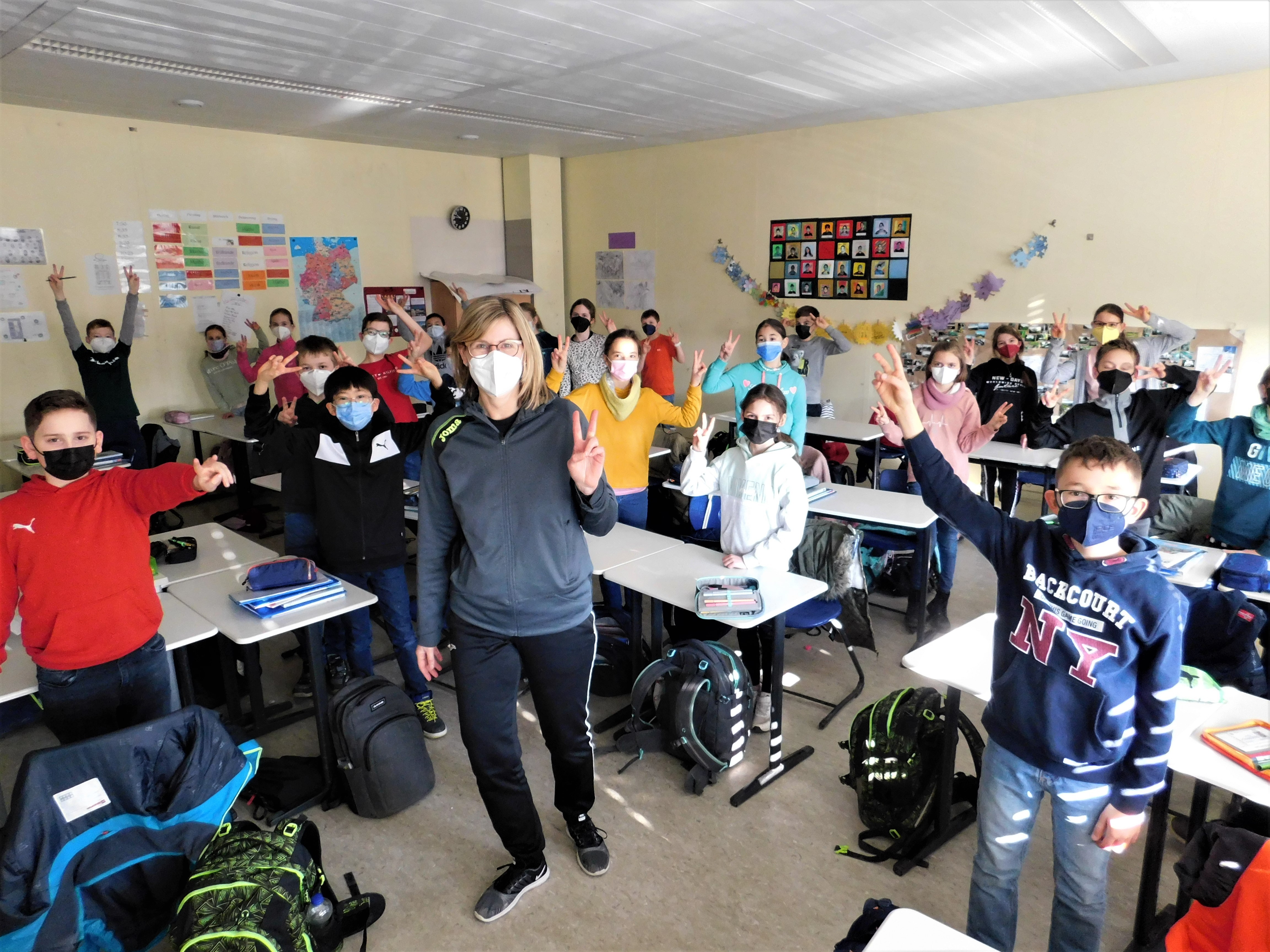 Kinder der fünften Klasse machen das Peace-Zeichen.