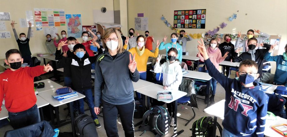 Kinder der fünften Klasse machen das Peace-Zeichen.