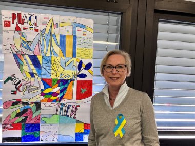 Die Schulleiterin vor einem Plakat.