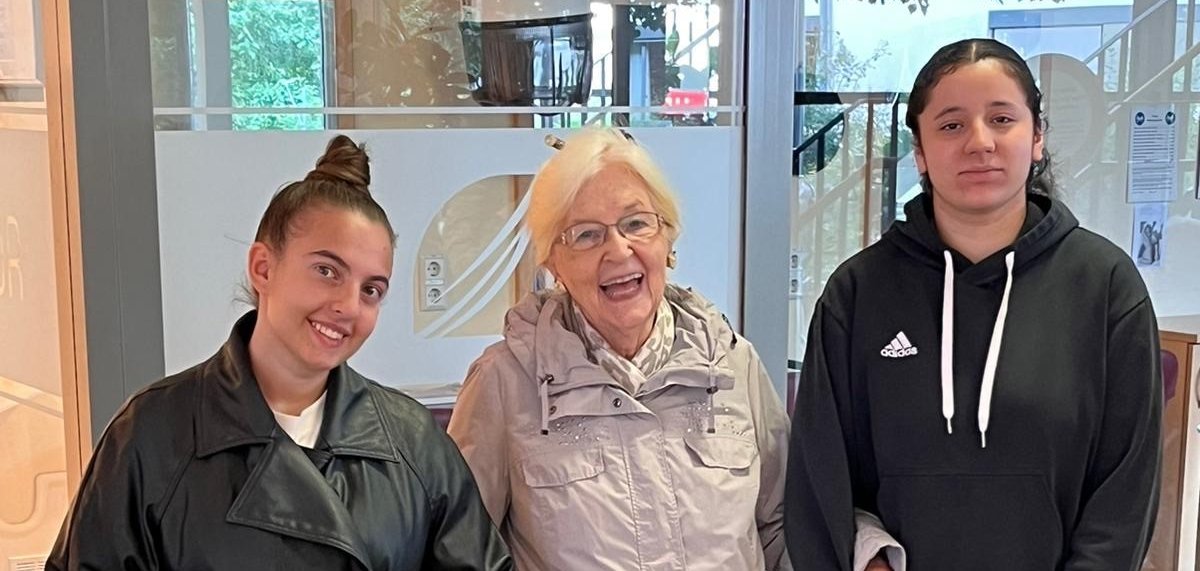 Eine Seniorin hat sich bei Jugendlichen eingehakt.