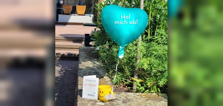 Der Wunschpass, eine Tasse und ein Ballon vor dem Rathaus.