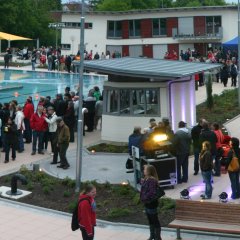 Einweihungsfeier im neuen Parkbad. Zu sehen sind feiernde Menschen rund um das Schwimmbecken.