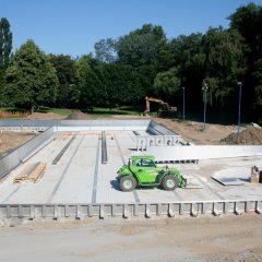 Blick in das künftige neue Schwimmbecken. Mittendrin steht eine Baumaschine.