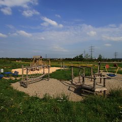 Blick über den Ziegeleipark Kriftel. Im Vordergrund verschiedene Spielgeräte und im Hintergrund die Frankfurter Skyline.