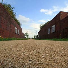 Blick entlang des von Ziegelmauern gesäumten Weges.