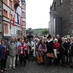 Gruppenbild einer Seniorengruppe bei einem Ausflug auf einem Platz einer Altstadt