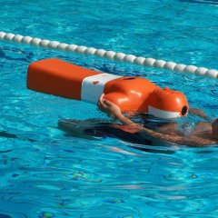 Ein Schwimmer zieht eine Rettungspuppe im Wasser hinter sich her
