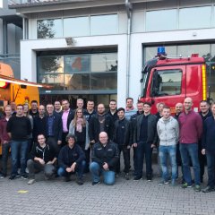 Ein Gruppenbild der Helfer der Freiwilligen Feuerwehr vor einem Imbisstand und einem Einsatzfahrzeug