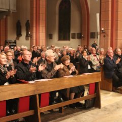 Blick von vorne auf applaudierende Besucher der katholischen Kirche während einer Veranstaltung im Innenraum