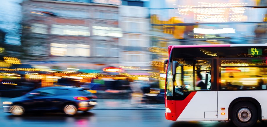 Bild mit Bus und Auto im Straßenverkehr.