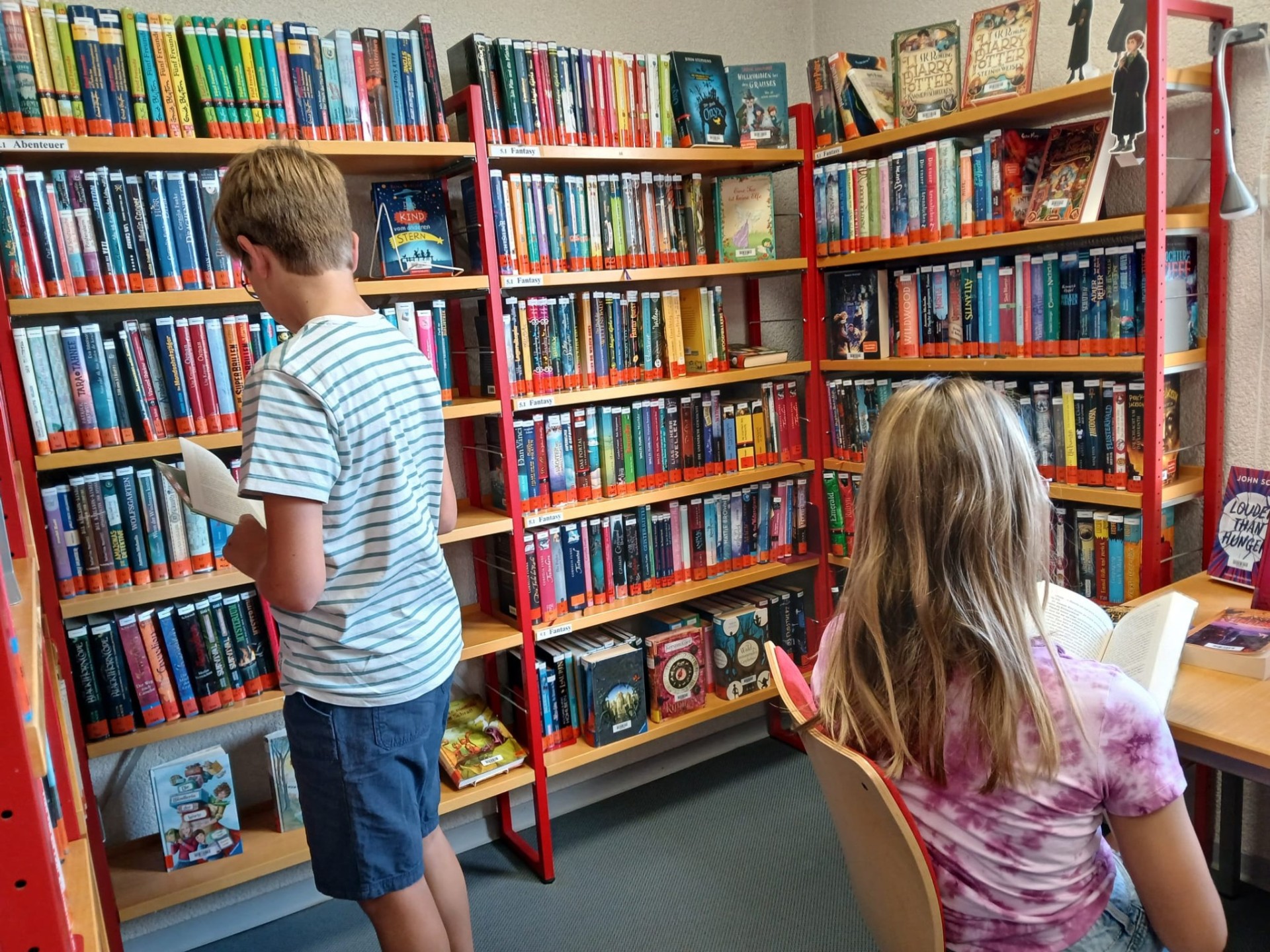 Kinder vor Bücherregalen.