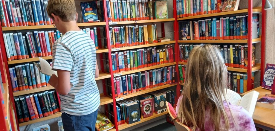 Kinder vor Bücherregalen.